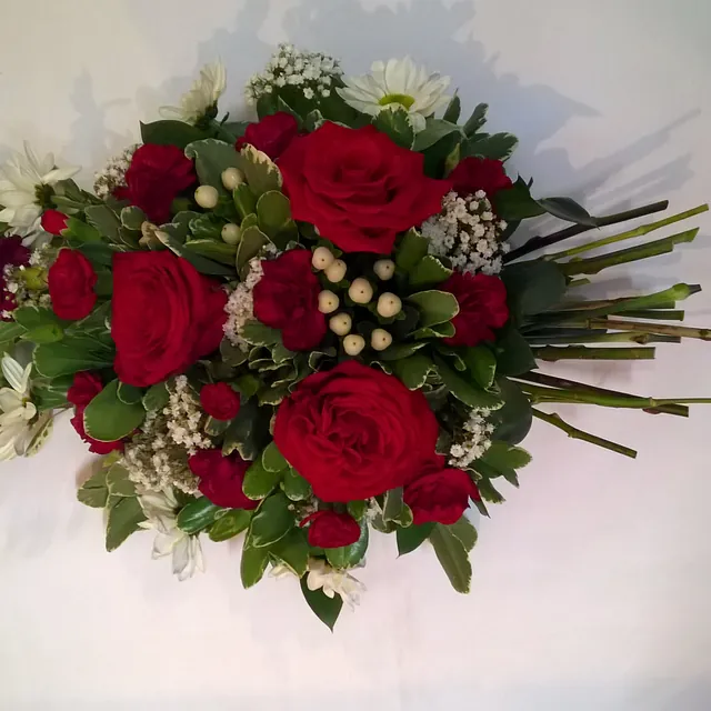 Open Spray / Sheaf in Oasis red roses with white filler flowers .